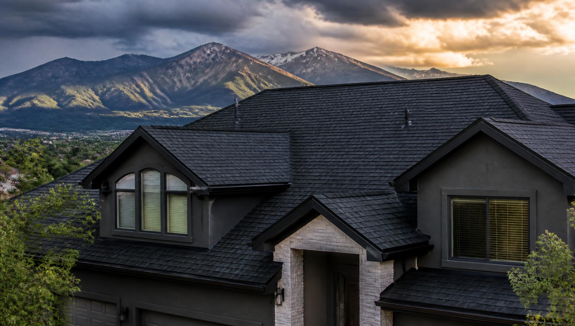 Newly installed dark architectural shingle roof on a Colorado home with Pikes Peak behind it